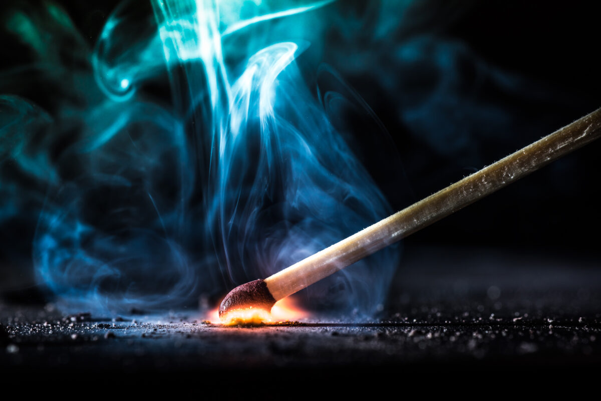 A match being struck, igniting a small flame that symbolizes the spark of an idea or a new beginning.